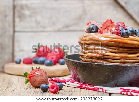 chocolate pancake with berries and caramel glaze in a rustic pan