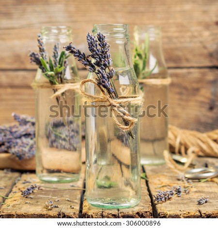 decorated with herbs and flowers bottle with a lavender lemonade on a wooden table. toned image
