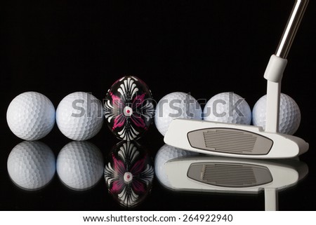 Golf equipments and egg on a black glass desk