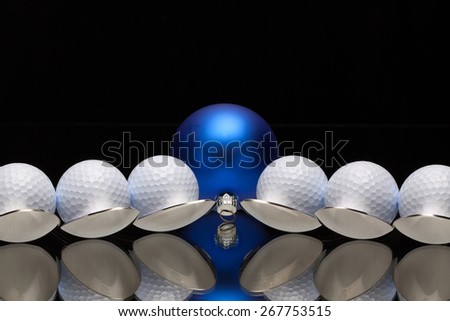 Blue Christmas decoration and six spoons with golf balls on a black glass desk