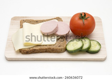 Bread with cheese, tomato, cucumber and salami  on board isolated on white background