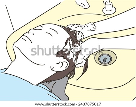 A young man gets shampooed while lying on his back at a shampoo table in a beauty salon