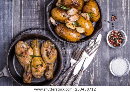 Country style potatoes and chicken with rosemary, garlic on a wooden dark background