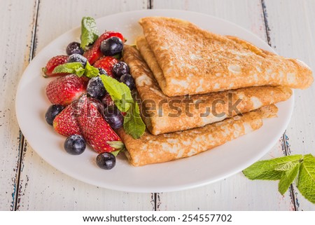 Homemade crepes with berries and fruit on a white background