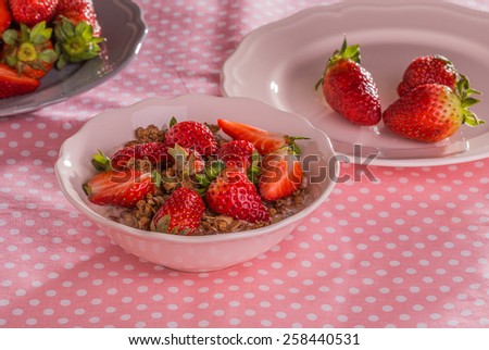 Chocolate cereal with milk and strawberries on pink textile background.
