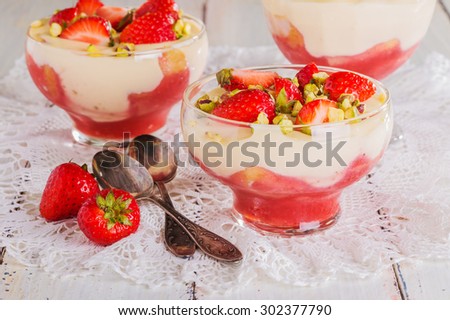 Strawberry tiramisu decorated with pieces of strawberries and pistachios on a white background