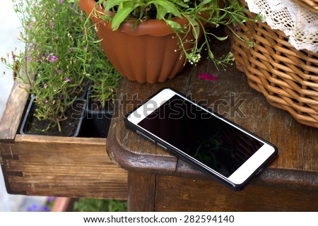Template. Phone on a wooden table, around the flowers in the baskets.