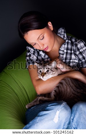 Happy young woman with cat, relaxed on the beanbag couch.g woman with cat, relaxed on the beanbag couch.