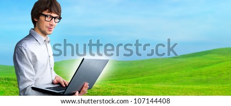 Portrait of a young man with laptop outdoor at countryside