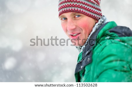 Satisfied smiling man standing in the green jacket outdoors