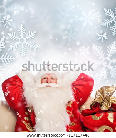 Santa Claus sitting with a sack indoor relaxing on silver snowflakes background