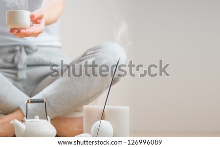 Woman sitting on floor of her home and holding tea cup. Aromatherapy, meditation and healthy life concept. Lots of copy space