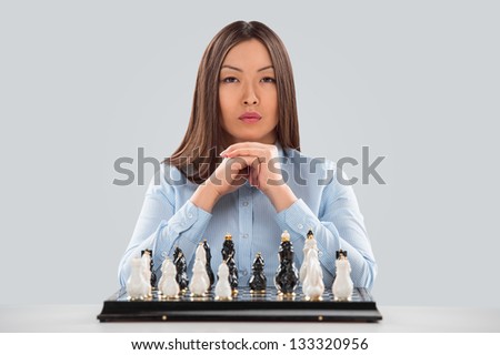Concept of Strategy in business - business woman sitting in front of chess and planning