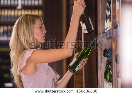Woman in a supermarket comparing two wines - white and red