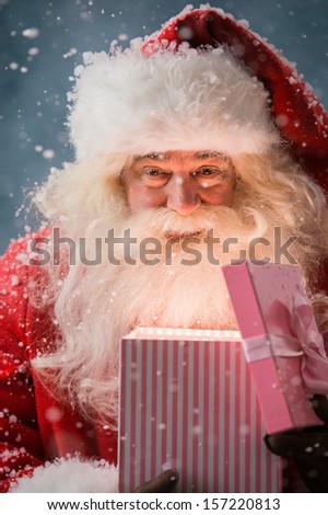 Happy Santa Claus opening his Christmas gift at North Pole