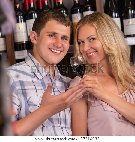 Young couple degustating red wine at supermarket