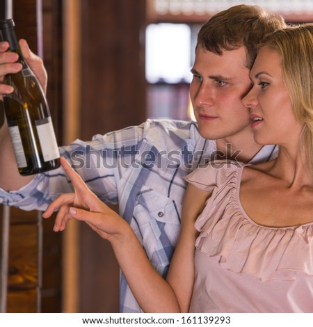 Young couple chooses the wine at supermarket
