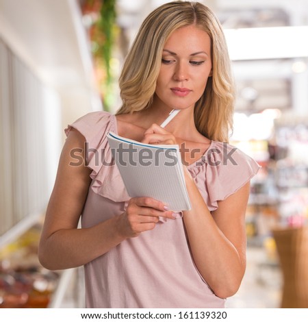 Shopping list - woman using shopping list at grocery store
