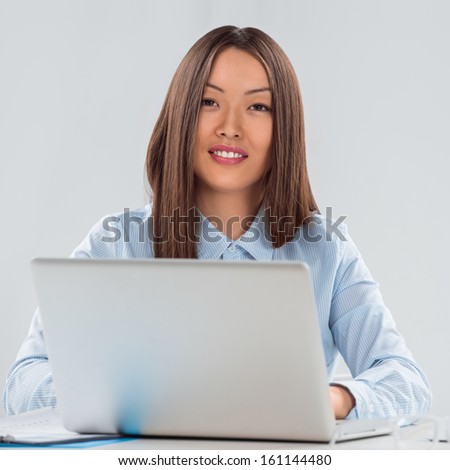 Portrait of a happy young female business executive working on laptop in the office