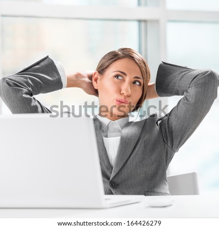 Beautiful female executive relaxing with hands behind head