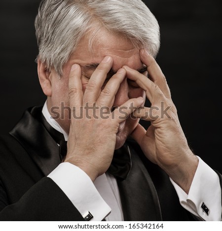 Portrait of a mature business man looking depressed from work over black background
