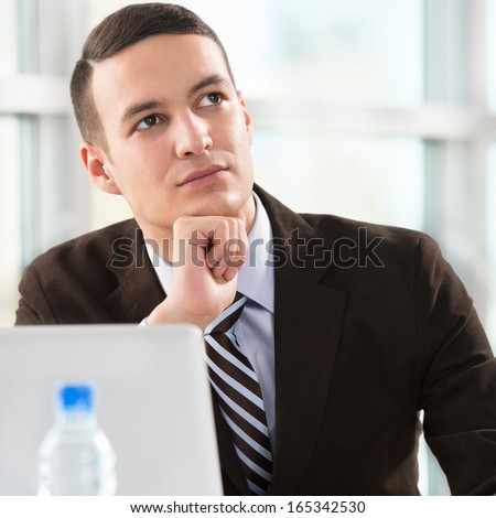 Business man at his office working with laptop and thinking about his future plans