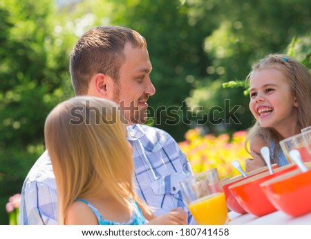 Family eating together outdoors at summer park or backyard