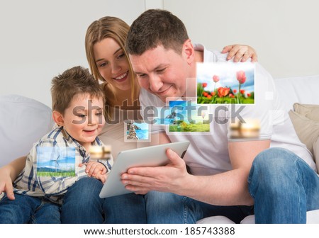 Young happy family watching their photo and video files using modern tablet computer