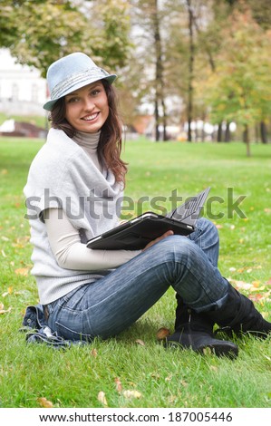Young woman using tablet computer outdoor sitting on grass