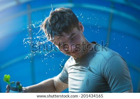 Man fitness runner drinking and splashing water in his face. Funny image of handsome male refreshing during workout