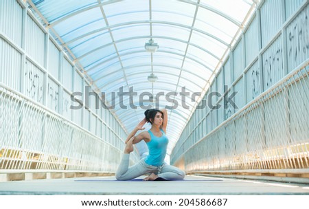 Woman doing stretching yoga exercises outdoors on the bridge. Full Length