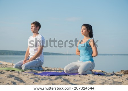 Morning Yoga Meditation at the Beach by young couple