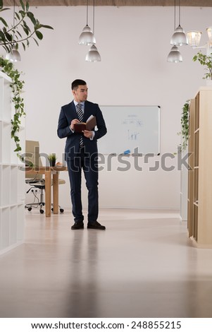 Portrait of a busy businessman taking notes and writing something in his organizer at his office