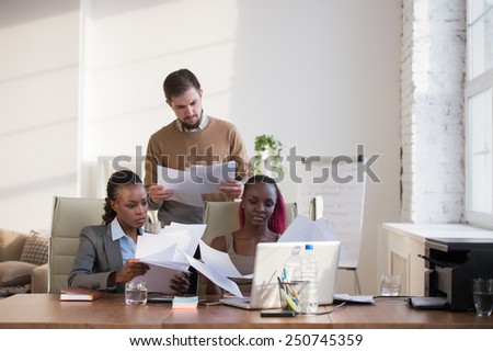 Image of group of three young business people of different ethnicity working together