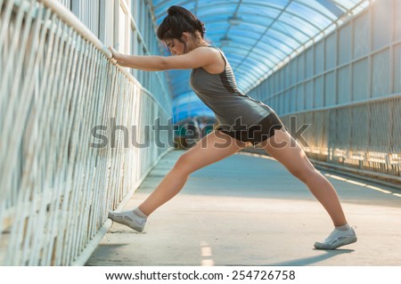 Fit young woman stretching before a run. Young female runner stretching her muscles before a training session