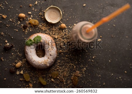 Sugar powder Donut with mint leaf and milk bottle on dark stone background
