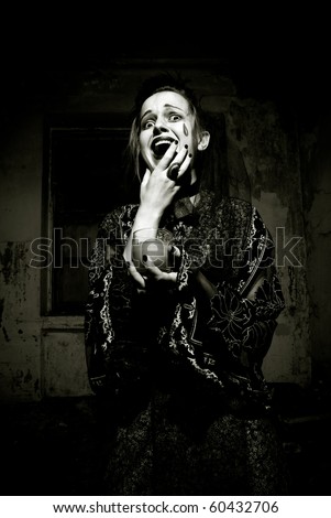 Young emotional gothic woman hanging candle in empty grunge dark room