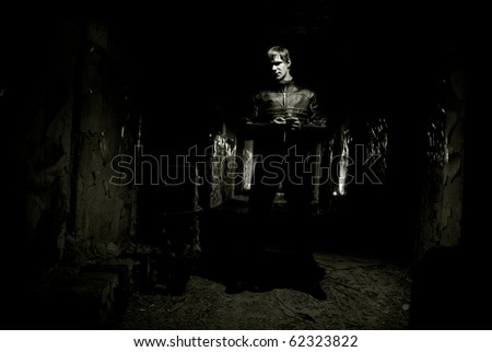 Portrait of young man inside abandoned building against vintage wall