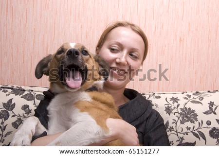Young woman playing with her dog on sofa in her apartment