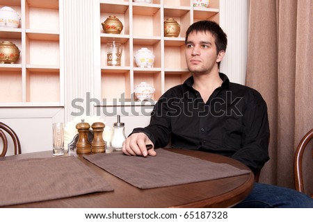 Portrait of young, handsome man thinking and waiting for woman in cafe