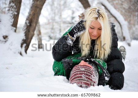 Young happy smiling couple in love playing snowballs and laying on snowdrift in winter park. Lifestyle Portrait