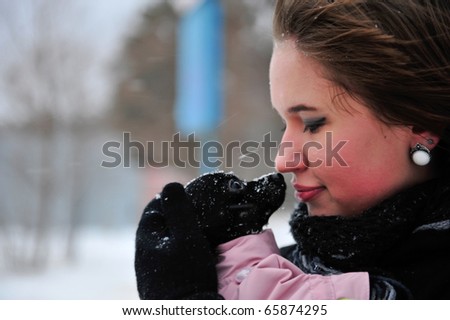 Outdoor portrait of young beautiful european style woman - holding her little dog in her arms and warming it. Care and liability concept