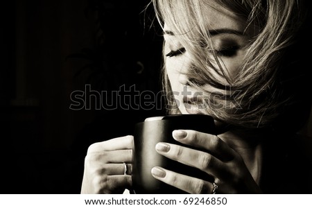 Portrait of adult attractive woman indoor in dark room drinking coffee