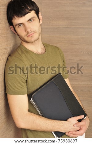 Portrait of handsome young entrepreneur holding folder with important papers and wearing casual clothes standing relaxed against modern wooden wall