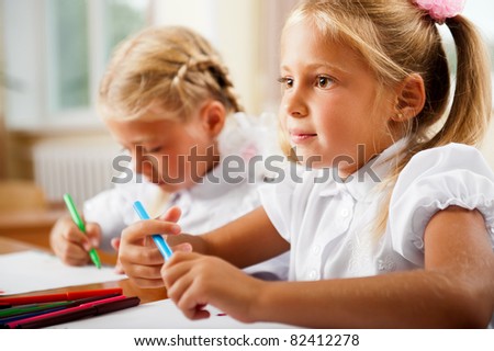 Little girls drawing pictures and writing letters to Santa Claus to get christmas gifts. Indoor at classroom