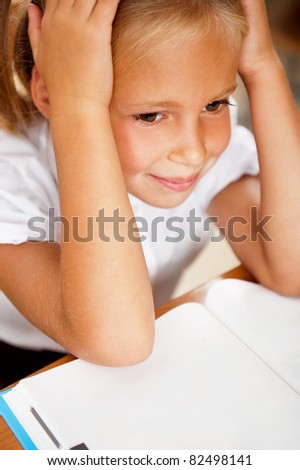 Image of smart child reading interesting book in classroom. Vertical Shot. She is tired