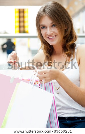 Happy shopping woman with bags and smiling. She is shopping inside mall