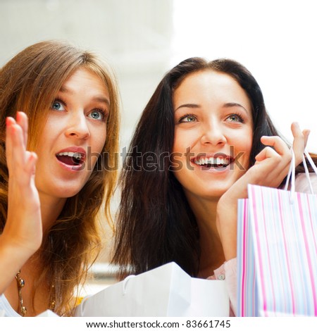 Two excited shopping woman together inside shopping mall, surprised about low prices and sales before christmas and boxing day. Horizontal Shot