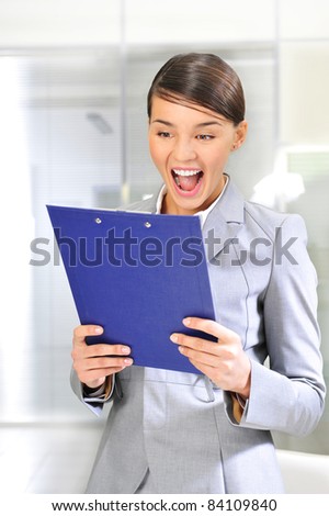 A portrait of a young business woman in an office with documents in her arms
