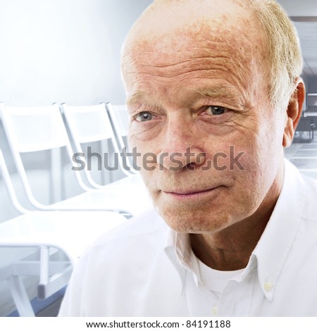Portrait of a happy senior man smiling over bright background of hospital hall